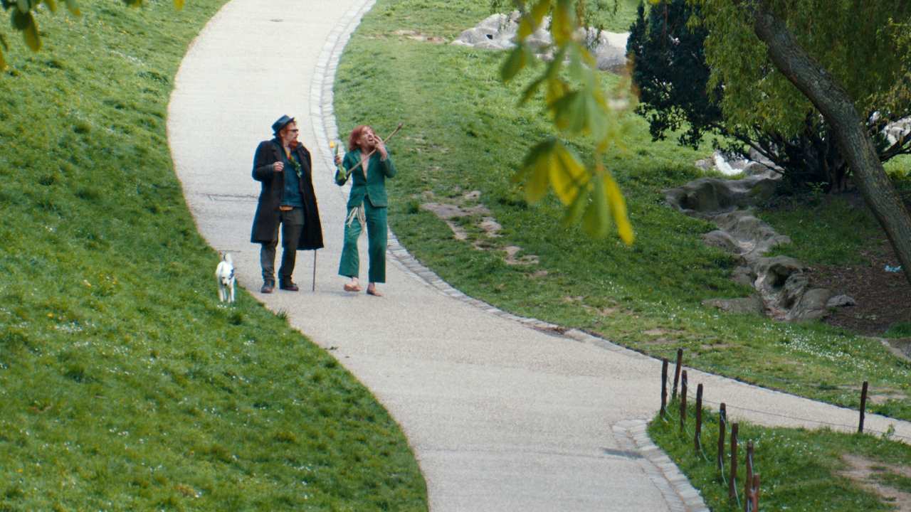 a man and woman walking a dog down a path